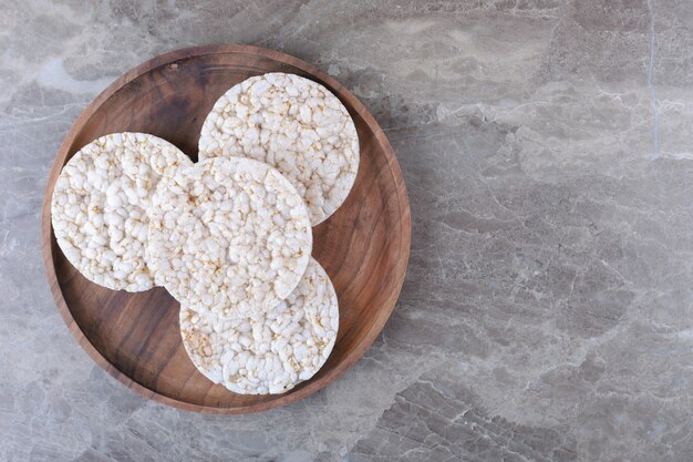 A pile of puffed rice cakes on the wooden tray, on the marble surface