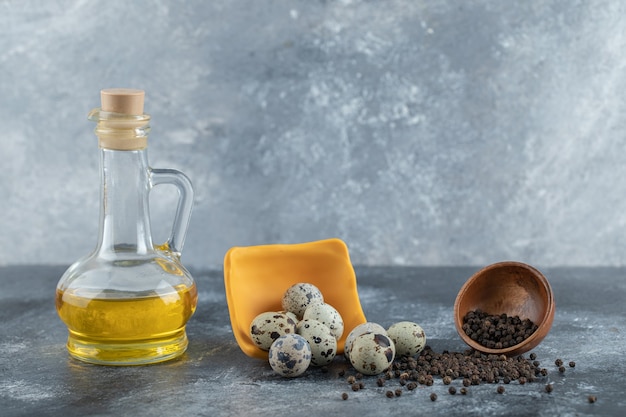 Pile of quail eggs on grey background with oil and spice