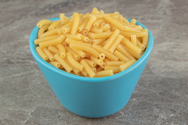 Pile of raw macaroni in blue bowl