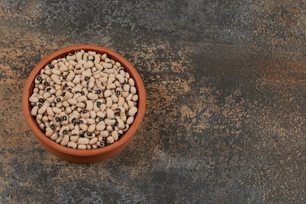 Pile of raw white beans in ceramic bowl. 