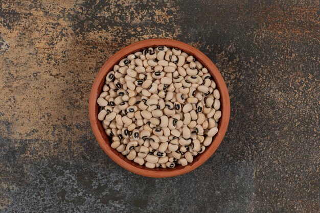 Pile of raw white beans in ceramic bowl. 