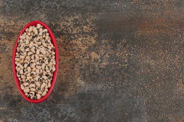 Pile of raw white beans in red bowl. 