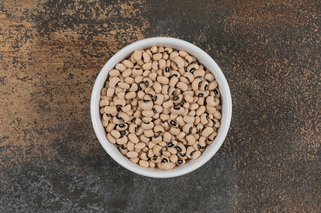 Pile of raw white beans in white bowl. 