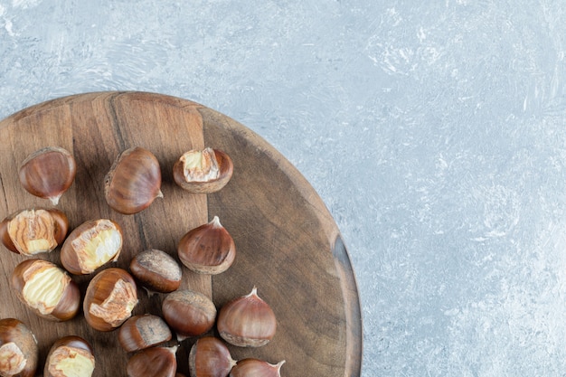 Pile of roasted chestnuts on wooden board.