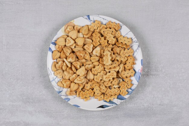 Pile of salted crackers on colorful plate.