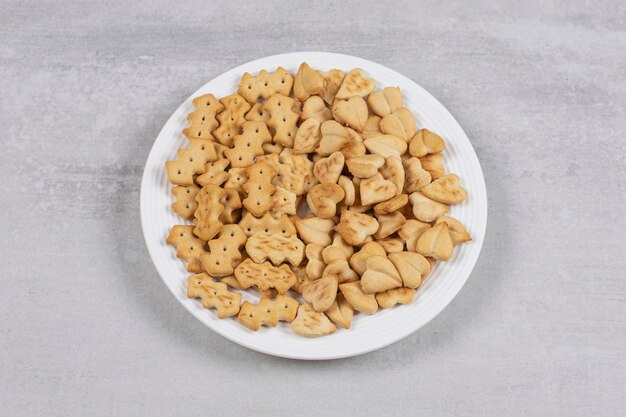 Pile of salted crackers on white plate.