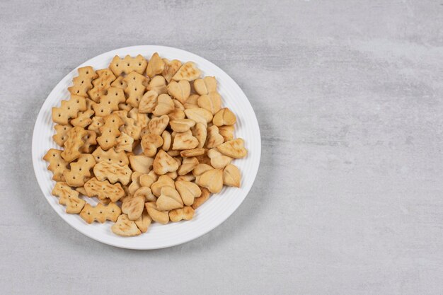 Pile of salted crackers on white plate.