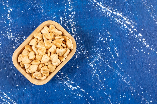 Pile of salted heart-shaped crackers placed in wooden bowl
