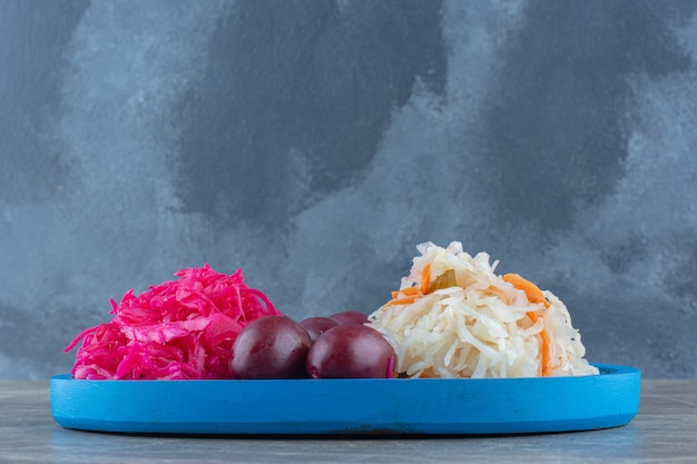 Pile of sauerkraut. Red and white on blue wooden plate.