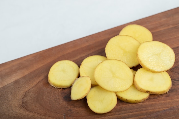 Pile of sliced potato on wooden board.