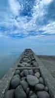 Free photo pile of stones on the beach with blue sky and clouds in the background