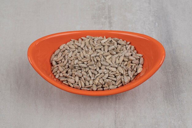 Foto gratuita mucchio di semi di girasole in una ciotola arancione.