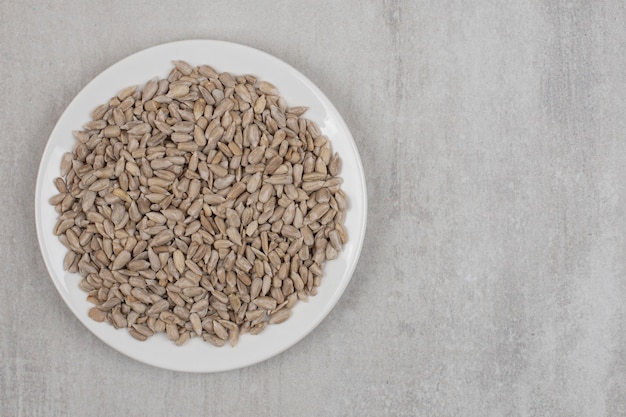 Pile of sunflower seeds on white plate.