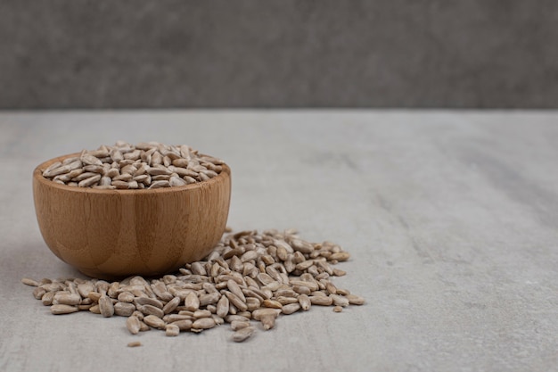 Pile of sunflower seeds in wooden bowl.