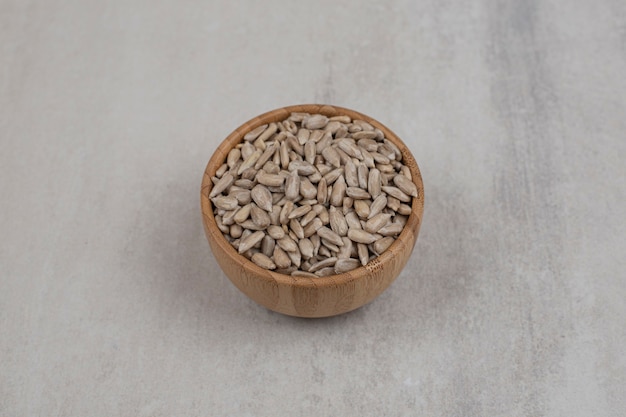 Pile of sunflower seeds in wooden bowl.