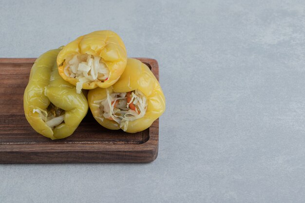 A pile of sweet peppers on the board on the marble surface