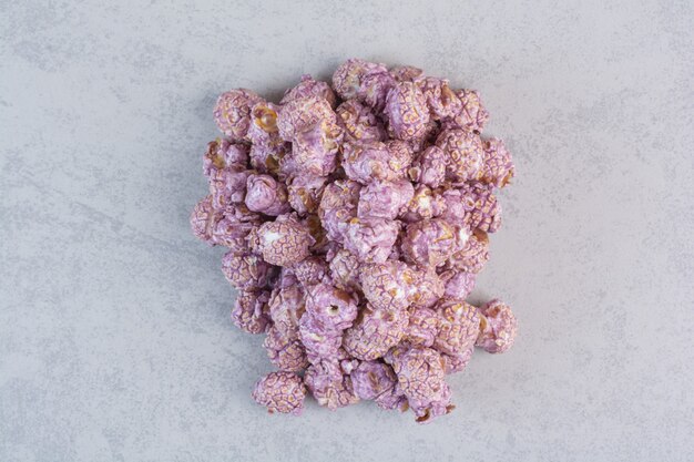 Foto gratuita pila di popcorn dolci ricoperti di caramelle viola su marmo.