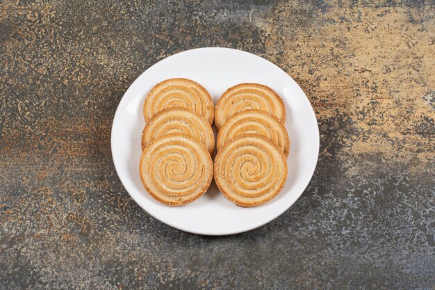 Pile of tasty round biscuits on white plate.