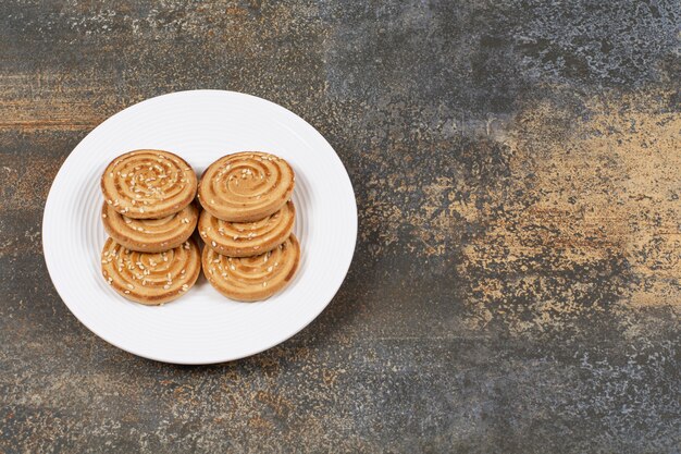 Pile of tasty round biscuits on white plate.