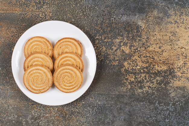 Pile of tasty round biscuits on white plate.