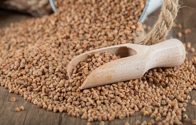 Pile of uncooked buckwheat on wooden spoon