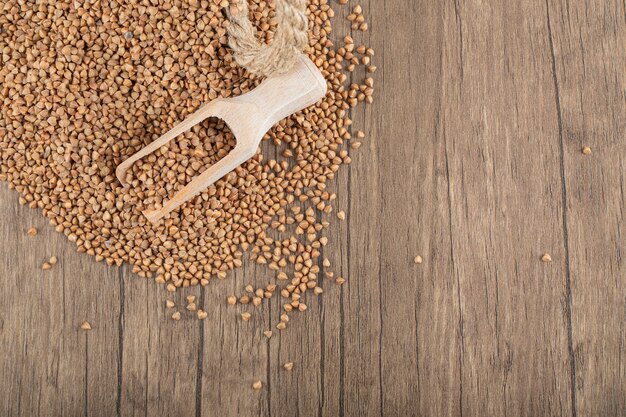 Pile of uncooked buckwheat on wooden spoon