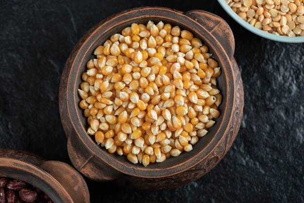 Pile of uncooked corn grains in ancient mug.