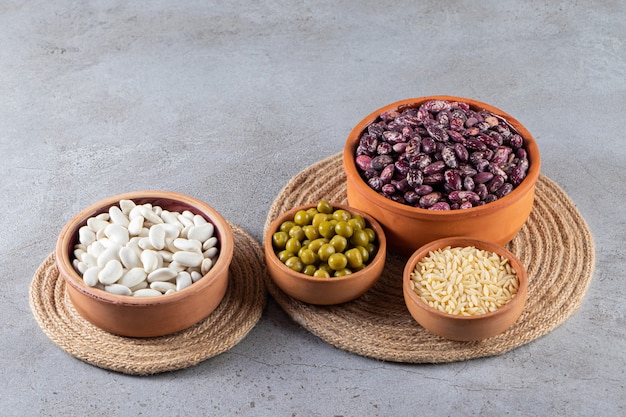 Pile of uncooked lentils, beans and rice on stone background. 