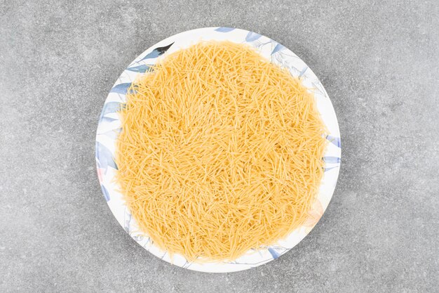 Pile of uncooked macaroni on white plate