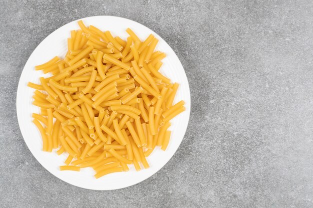 Pile of uncooked pasta on white plate