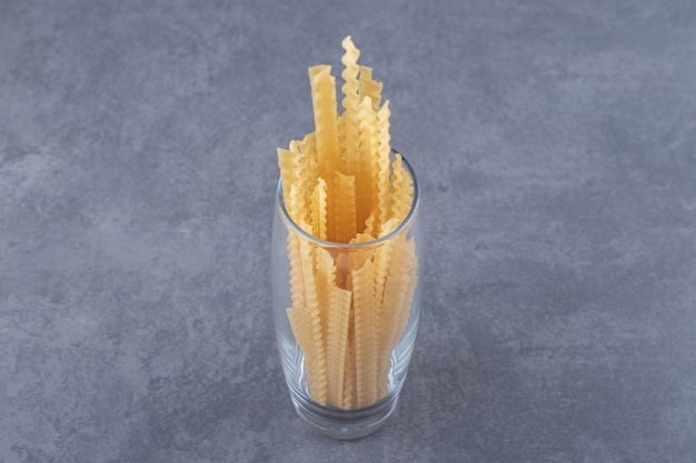 Pile of various-shaped dry pasta in glass.