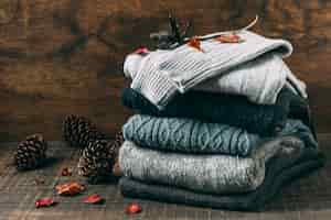 Free photo pile of winter sweaters with pine cones