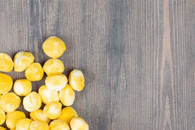 Foto gratuita mucchio di caramelle gialle su superficie di legno