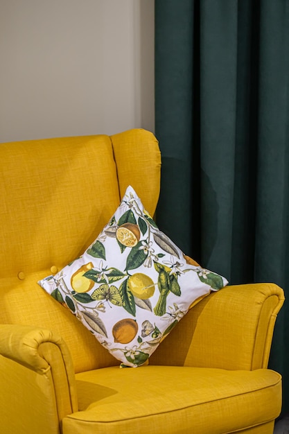 A pillow with lemons on a yellow armchair in the interior of the room