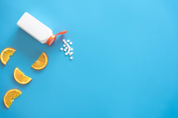 Pills are poured out of a jar on a blue background flat lay