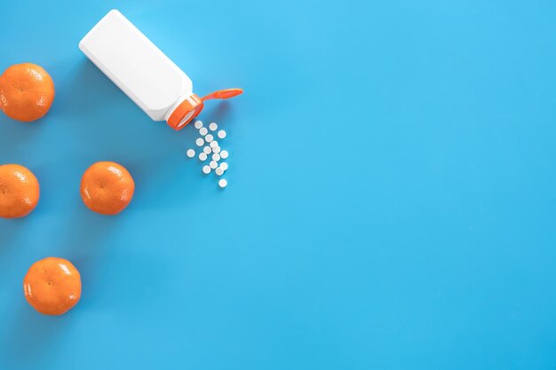 Pills are poured out of a jar on a blue background flat lay