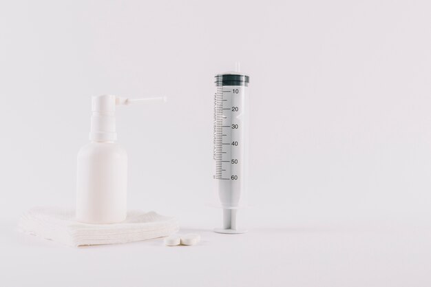 Таблетки; чистый белый аэрозоль с воздушным шаром на медицинской марле и пустой шприц для лечения