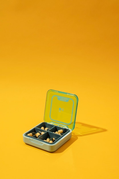 Free photo pills container with yellow background high angle