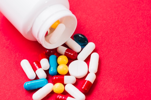 Pills of different colores and plastic bottle