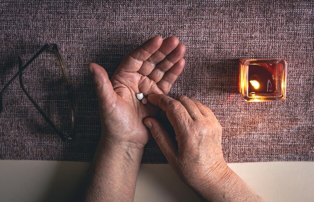 Free photo pills in the hands of an old woman top view