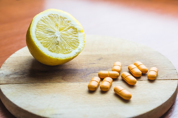 Free photo pills next to a lemon on a wooden surface