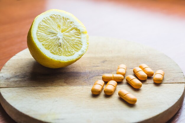 Таблетки рядом с лимоном на деревянной поверхности