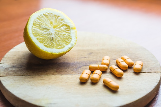 Pills next to a lemon on a wooden surface