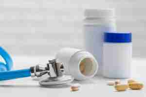 Бесплатное фото Таблетки или капсулы и стетоскоп на белом столе концепции здравоохранения