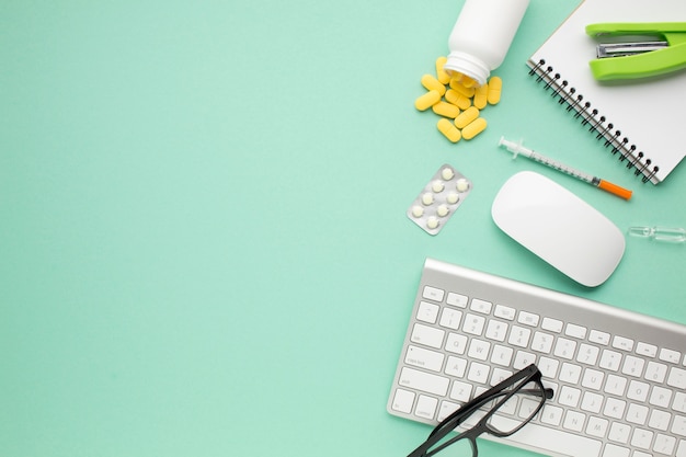 Pills and syringe with office accessories on green background
