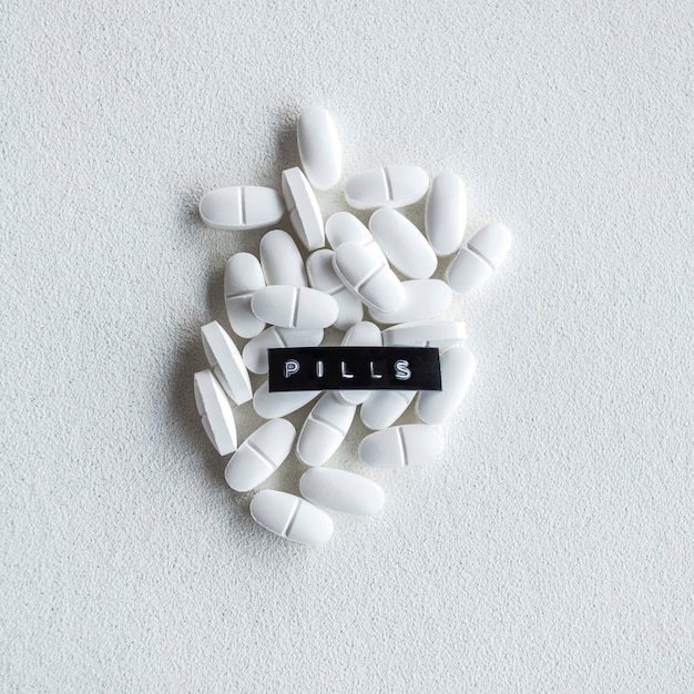 Текст таблеток над овальными белыми таблетками на грубом фоне