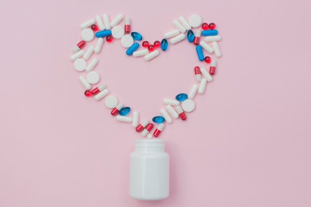 Pills with container on pink background
