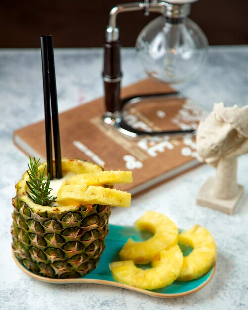 pinapple juice shake with straw and slices of pineapple