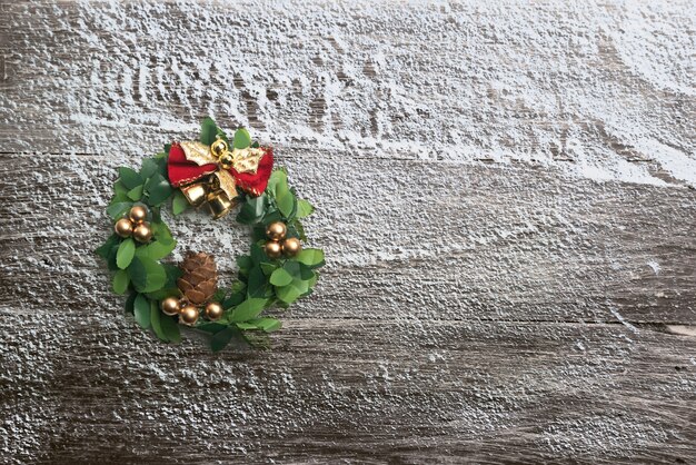 Сосновая шишка с колоколом на заснеженном деревянном фоне. рождественские украшения