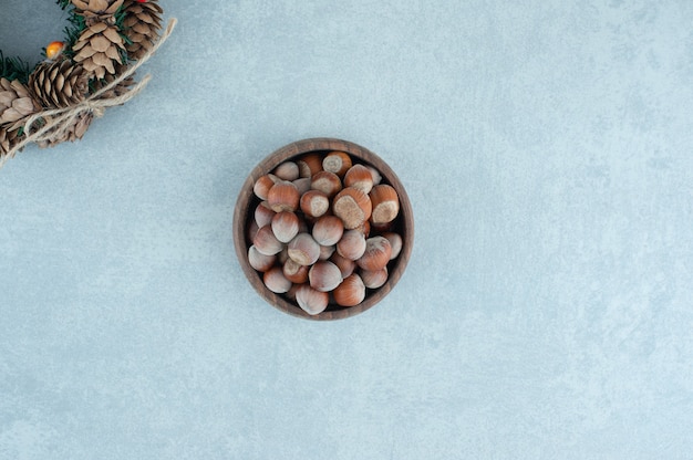 Pine cone wreath and bowl fo hazelnuts on marble.